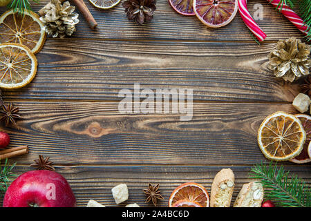 Natale accessori oggetti in legno marrone dello sfondo. Arance essiccate, Abete rami, golen connes, caramelle. Spazio per il testo. Copia dello spazio. Foto Stock