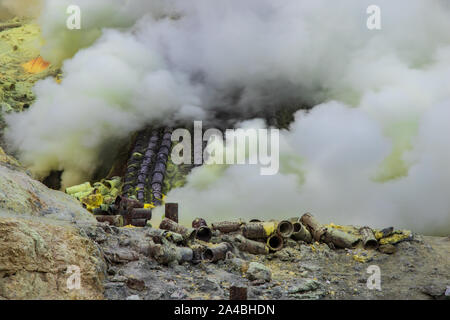 Miniere di zolfo il funzionamento in Mount Ijen cratere, Java Orientale, Indonesia. Gas tossici in fuga da bocche vulcaniche. Foto Stock