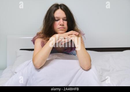 Triste adolescente ragazza seduta a casa a letto. Foto Stock