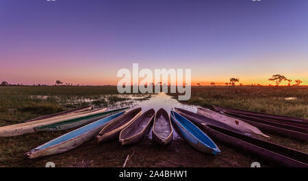 Botswanian mokoro locale barche nel tramonto sulla riva del delta del fiume Okavango, Botswana Foto Stock