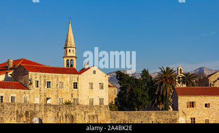 Il tardo pomeriggio di sole rende le mura della città vecchia di Budva candelette Foto Stock