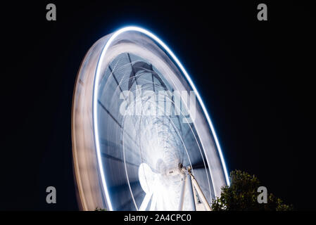 Ruota panoramica Ferris la filatura lunga esposizione neon struttura contro la notte nera a La Rochelle Foto Stock