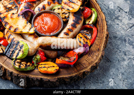 Salsicce alla griglia e verdure con salsa ketchup sul vassoio.in legno alimenti barbecue Foto Stock
