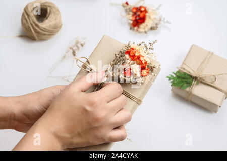 Creative craft di Natale fatti a mano hobby. Donna mani presenta la decorazione con fiori secchi e foglie di pino per Natale e Capodanno o altri anniversar Foto Stock