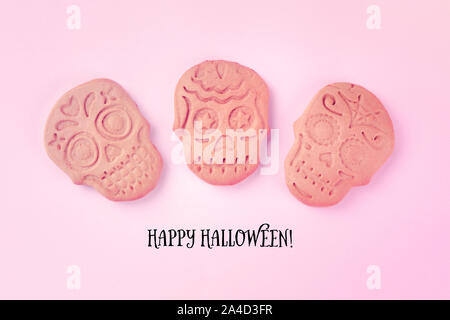 Happy Halloween biglietto di auguri con cranio biscotti allo zenzero, girato dalla parte superiore su un sfondo rosa Foto Stock