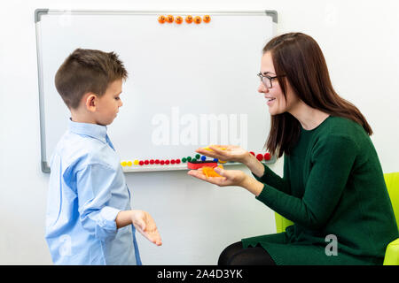 I bambini di terapia del linguaggio concetto. Preschooler alla terapia del linguaggio facendo esercizi di respirazione con una femmina di logopedista. Foto Stock