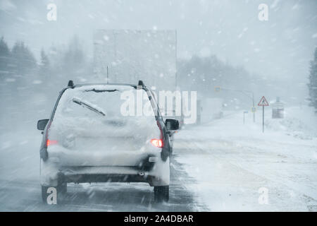 Egli auto è la guida su una strada in inverno in una bufera di neve Foto Stock