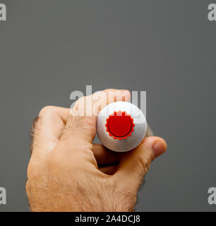 Man mano che tiene la maionese senape il tubo con il tappo rosso Foto Stock