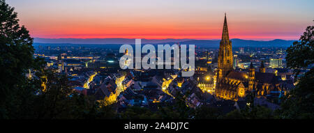 Germania, XXL panorama di colorati di rosso tramonto cielo illuminato di decorazione skyline di foresta nera città Freiburg im Breisgau, visto da antenna di cui sopra dopo Foto Stock