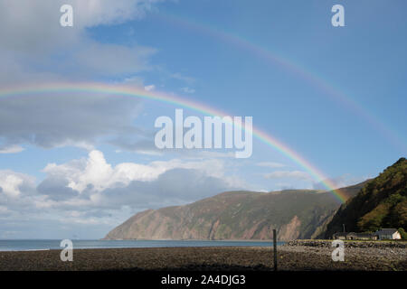 Rainbow oltre il mare e la baia di Lynmouth, Devon, vista dell'Foreland, cielo blu arcobaleno, REGNO UNITO Foto Stock