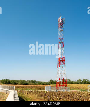 5G antenna per la connessione internet ad alta velocità di distribuzione. 5G di ripetitori fuori città. Colori luminosi rosso e bianco. Foto Stock