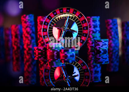 Tema del casinò. Giochi d'azzardo. Roulette, Dadi e poker chips su un colorato sfondo bokeh di fondo. Foto Stock