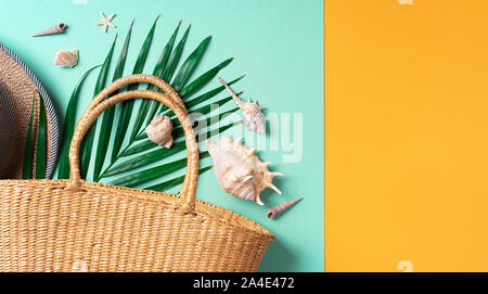 Moda estate laici piana. Elegante borsa di paglia, cappello, foglie di palma, gusci su giallo alla moda e sfondo verde. Vista dall'alto. Copia dello spazio. Lifestyl sostenibile Foto Stock