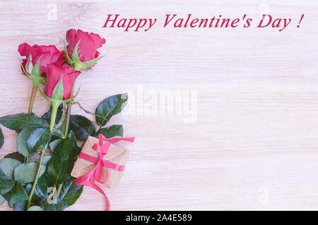 Bouquet di rose rosse con craft confezione regalo e nastro rosso su bianco sullo sfondo di legno. San Valentino con il concetto di spazio di copia Foto Stock