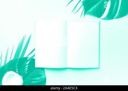Green monstera, foglie di palma, di cocco, di notebook su verde alla moda e colore turchese. Femmina scrittore blog workspace, torna al concetto di scuola. Mint colo Foto Stock