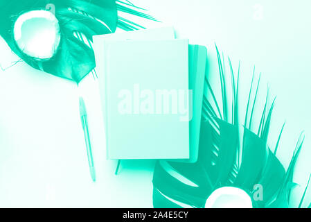 Femmina scrittore blog concetto di area di lavoro. Monstera Verde foglie di palma di cocco, sul verde alla moda e colore turchese. Mint colore di sfondo con una copia dello spazio. Foto Stock