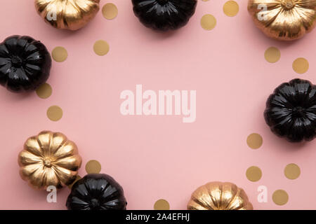 Oro e nero zucche sul rosa pastello. Appartamento laici composizione del ringraziamento Foto Stock