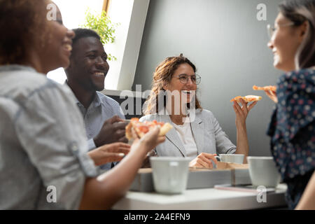 Società multirazziale membri aventi il pranzo di mangiare la pizza durante la pausa Foto Stock