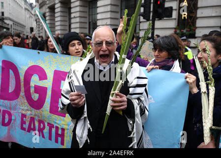 Rabbi Jeffrey Newman si unisce a manifestanti bloccando la strada al di fuori Mansion House nella città di Londra, durante un XR il cambiamento climatico protesta. Foto Stock