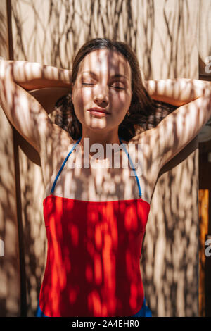 Giovane donna, a prendere il sole sotto l'ombra di una palma. Foto Stock