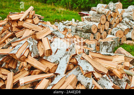 Sullo sfondo di una pila di dividere i registri in un woodpile per uso come riscaldamento domestico in inverno con una vista ravvicinata della sezione trasversale in corrispondenza delle estremità. Foto Stock