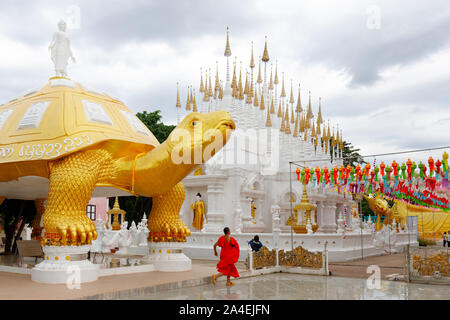 Il Wat Phong Sunan tempio buddista in Thailandia, con un monaco che gira sotto la tartaruga gigante statua dorata. Foto Stock