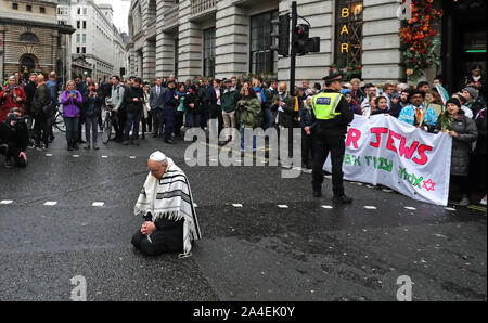 Rabbi Jeffrey Newman si unisce a manifestanti bloccando la strada al di fuori Mansion House nella città di Londra, durante un XR il cambiamento climatico protesta. Foto Stock