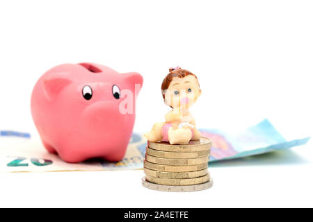 Una bambina su una pila di monete e un salvadanaio su banconote (concetto child support) Foto Stock