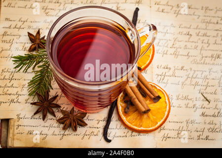 Hot vino speziato con spezie su un vecchio libro di cucina da sopra Foto Stock