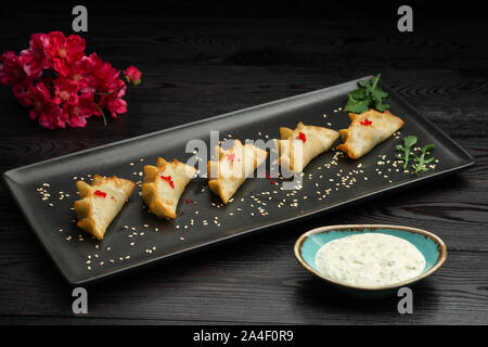 Ebi gedza cinese gnocco fritto con gamberi e verdure in una piastra nera su sfondo scuro, serviti con salsa Foto Stock
