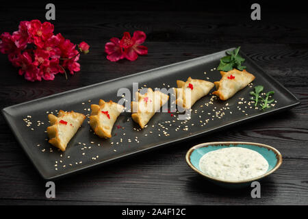 Ebi gedza cinese gnocco fritto con gamberi e verdure in una piastra nera su sfondo scuro, serviti con salsa Foto Stock