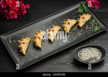 Ebi gedza cinese gnocco fritto con gamberi e verdure in una piastra nera su sfondo scuro, serviti con salsa Foto Stock