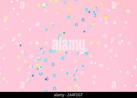 Colorato foglio olografico confetti sfondo. I cerchi color pastello rosa, blu e giallo sparse su carta di tendenza di colore rosa tenue. Vacanza semplice c Foto Stock