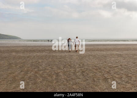 Giovane passeggiate sulla spiaggia di sabbia lasciando tracce nella sabbia. Un padre e sua figlia godendo il giorno. Giorno nuvoloso. Foto Stock