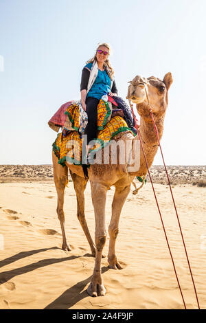 Un turista femminile su un cammello trek seduta in cima il suo cammello, il Deserto di Thar, Rajasthan, India. Foto Stock