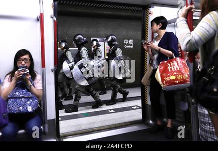 Ottobre 14, 2019, Hong Kong, Hong Kong, Cina: i passeggeri sul treno della metropolitana guarda come riot pattuglia di polizia attraverso la piattaforma di MTR Stazione Centrale con piena gli indumenti di protezione durante la massiccia rally. (Credito Immagine: © Liau Chung-ren/ZUMA filo) Foto Stock