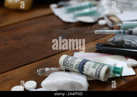 Un sacco di sostanze stupefacenti e dispositivi per la preparazione di farmaci si trovano su un vecchio tavolo di legno. Il TRAFFICANTE DI DROGA roba. La cocaina e la cannabis in completa Foto Stock