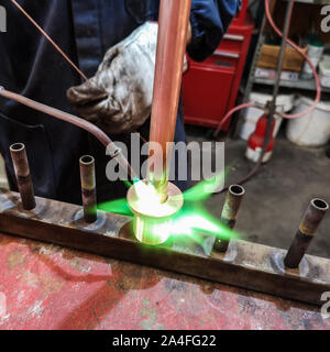 Particolare della saldatura di raccordi in ottone sul tubo di rame. Foto Stock