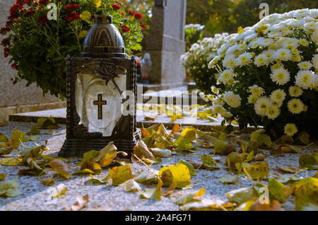 Lanterna con candela che brucia e giallo Foglie di autunno sulla tomba Foto Stock