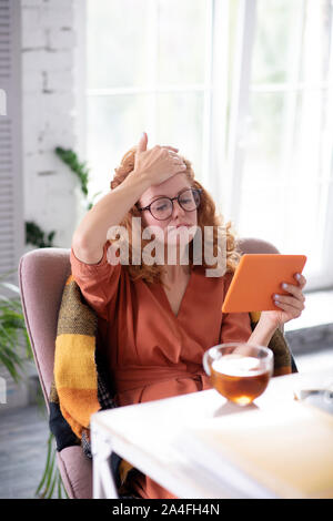 Curly freelancer toccando la fronte mentre un senso di vertigine Foto Stock