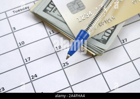 Penna e carta di credito su molte centinaia di noi le fatture del dollaro nella pagina calendario vicino. Attività di pianificazione finanziaria e concetto. Ragioniere lavoro Foto Stock