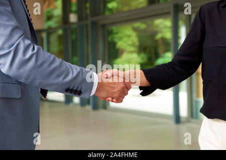 Close-up shot di business persone in piedi in ufficio e si stringono le mani. Foto Stock