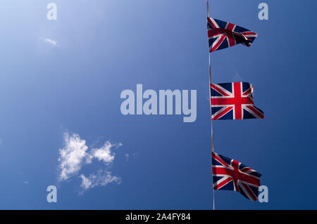 Tre battenti Union Jack Flag in un cielo chiaro Foto Stock