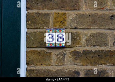 Il numero civico 38 in piastrelle su un muro di mattoni Foto Stock