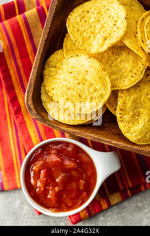 Mais rotonde nacho chips e pomodoro dip. Giallo tortilla chips e la salsa in un recipiente. Vista dall'alto. Foto Stock