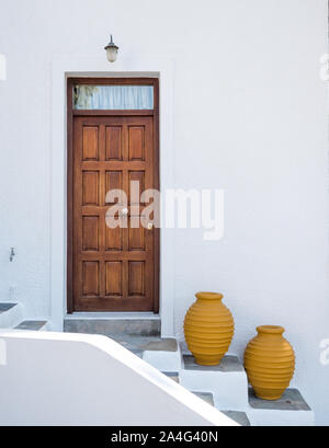 Un pannellate in legno porta con due senape colorata colorata pentole su passi contro il bucato bianco muro di cemento in Grecia Foto Stock