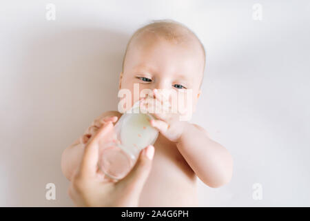 Un ritratto di carino neonato essendo alimentato da sua madre utilizzando la bottiglia. Foto Stock