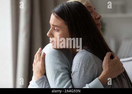 Vista laterale caring donna di mezza età calmante triste figlia millenario. Foto Stock