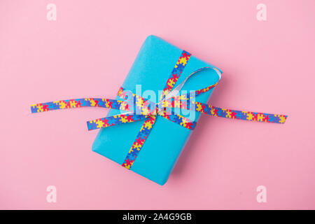 Mondo di sensibilizzazione sull'Autismo sfondo blu con dono su sfondo rosa. Foto Stock