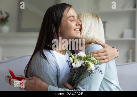 Felice giovane donna congratularmi con coppia mom con compleanno. Foto Stock